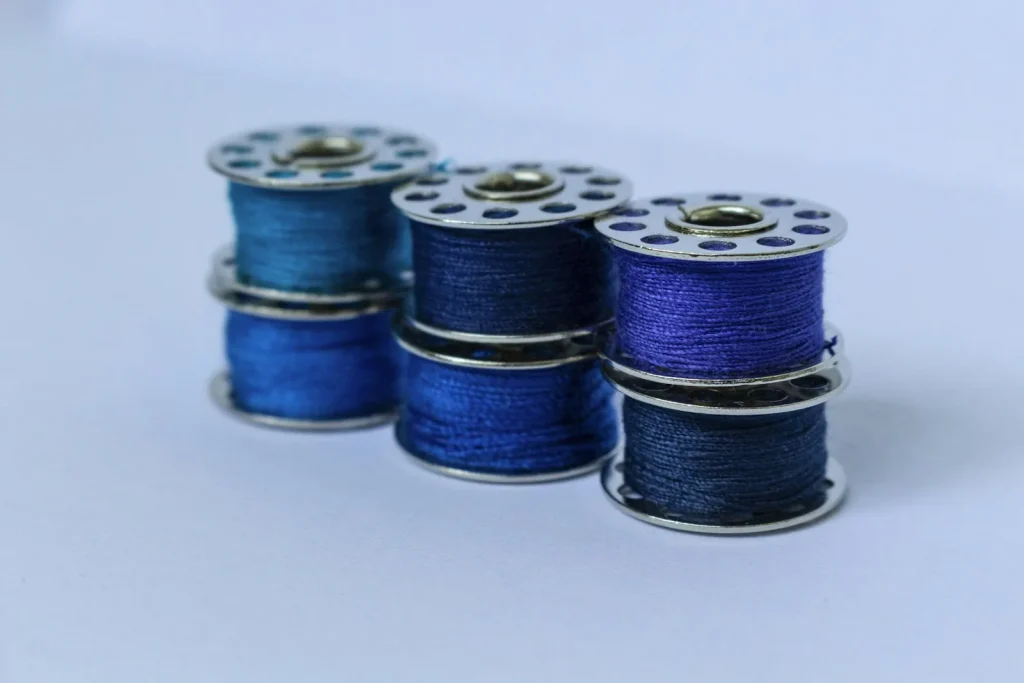 A metal bobbin case dangling from its thread tail during the drop test