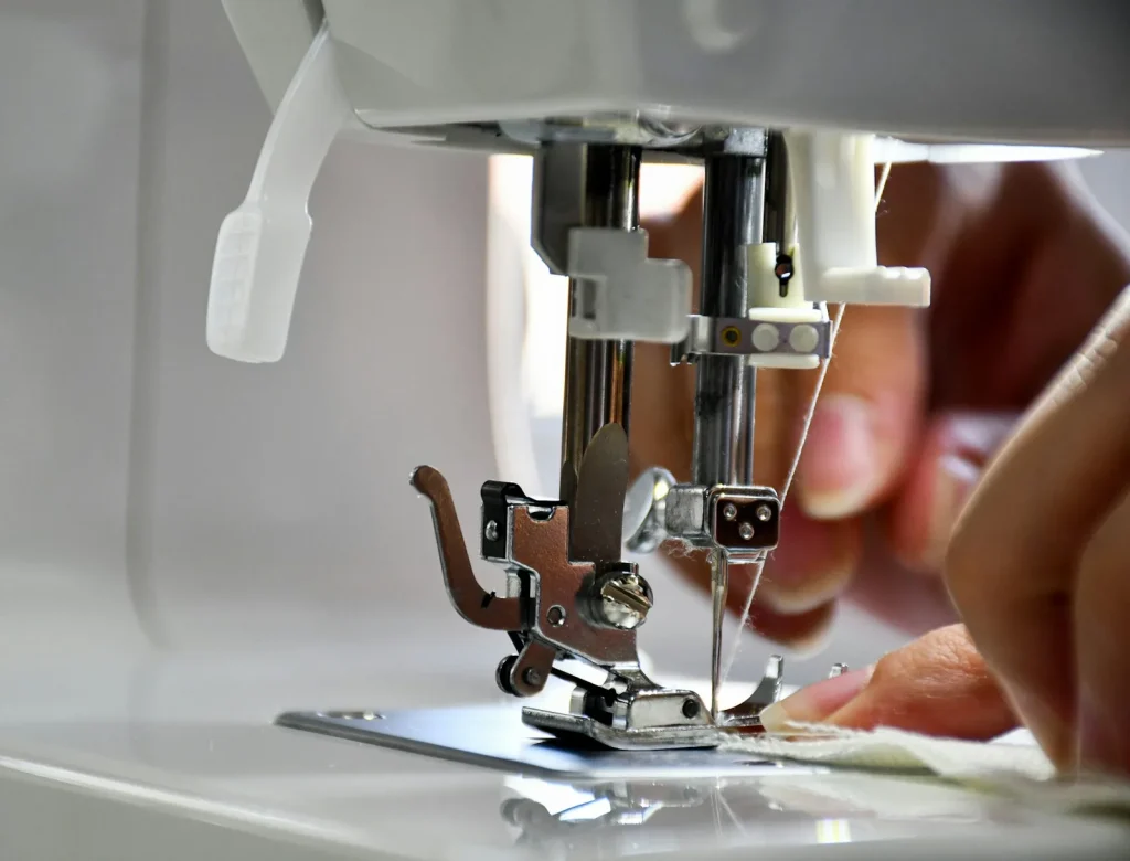 Sweeping packed lint out of the bobbin area with a small cleaning brush