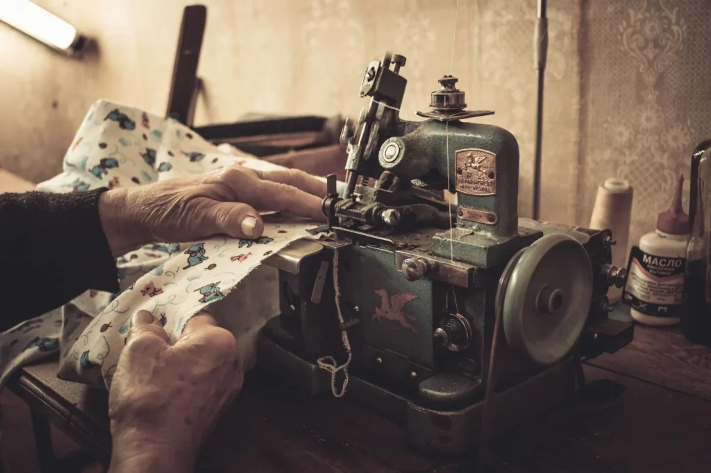 Hands applying a drop of oil to a marked point inside a sewing machine following the manual