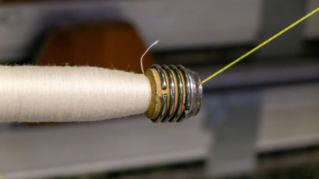 Freshly wound bobbin held up to the light showing an even thread surface