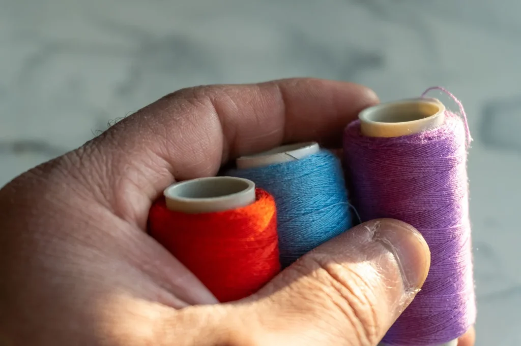 Checking a strand of thread against a window for a fuzzy halo of loose fibers