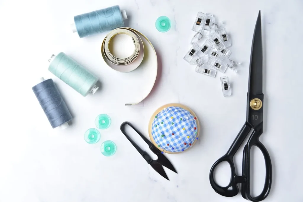 A palm sized handheld sewing machine stitching a seam on denim fabric