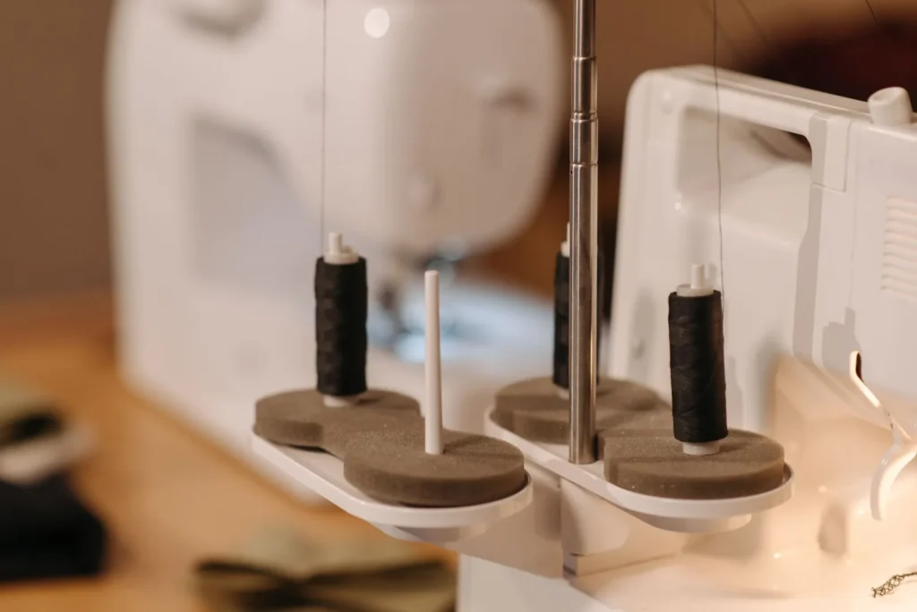 A lint brush, tweezers, and small screwdriver set laid out beside a sewing machine