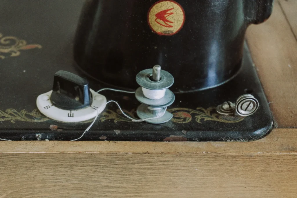A rubber bulb blower clearing lint from a sewing machine bobbin area