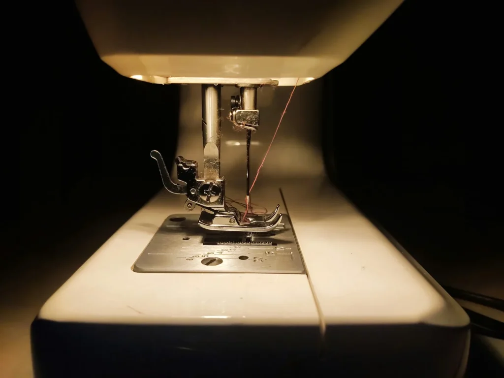 Foot pedal cord and plug connection at the base of a sewing machine