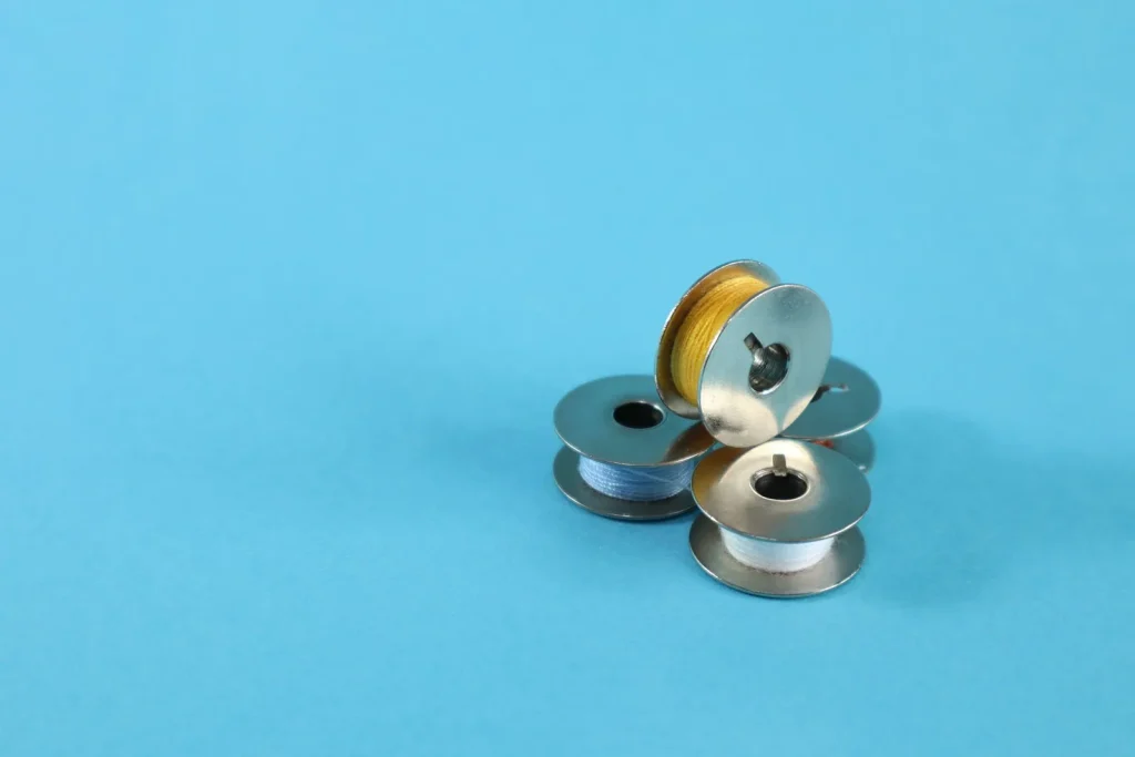 Top thread seated between the metal tension discs on the front of a sewing machine