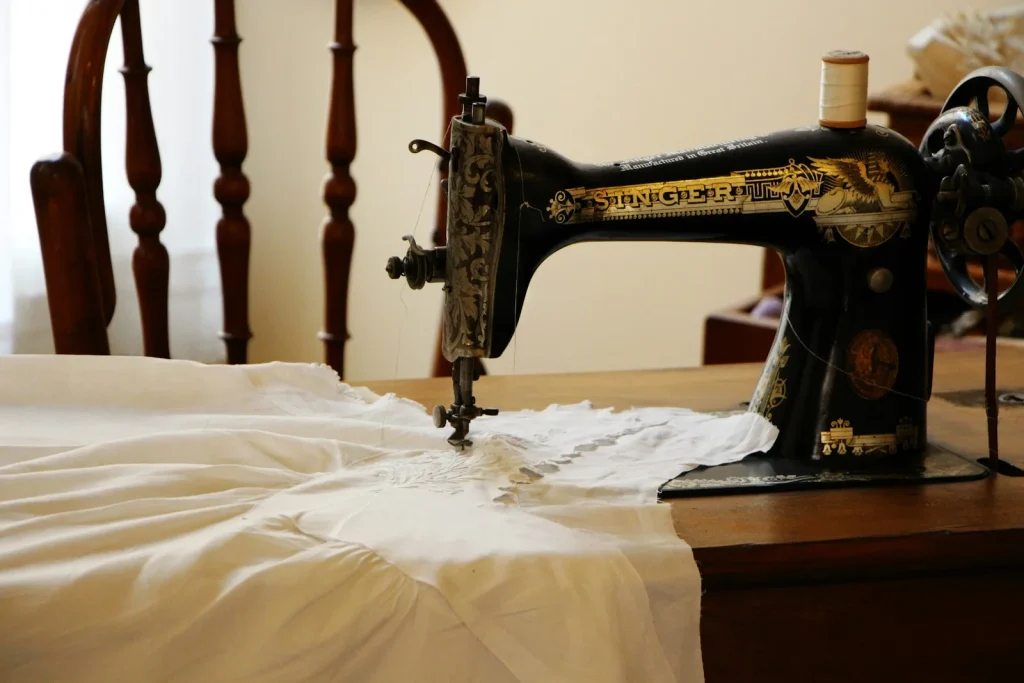 A quilted dust cover draped over a sewing machine resting on a closet shelf