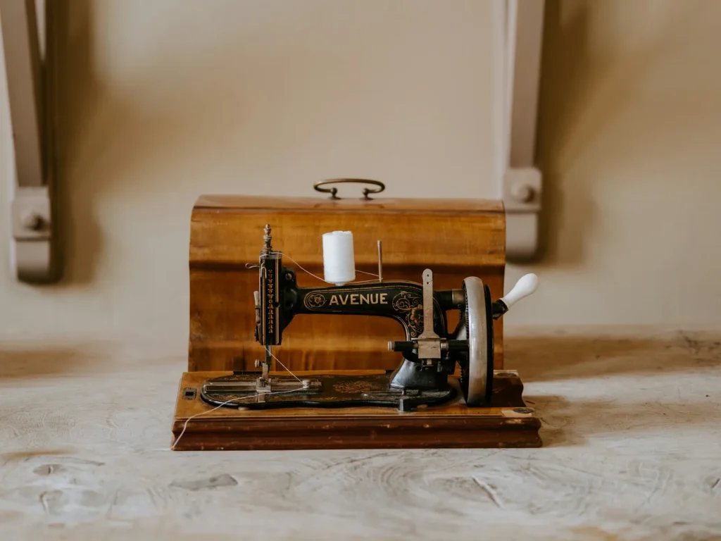 A sewing machine resting in its molded hard case with a silica gel packet tucked beside it