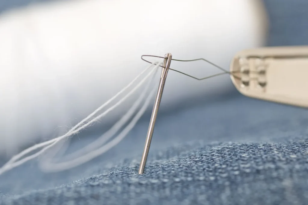 Two parallel needles stitching a folded knit hem