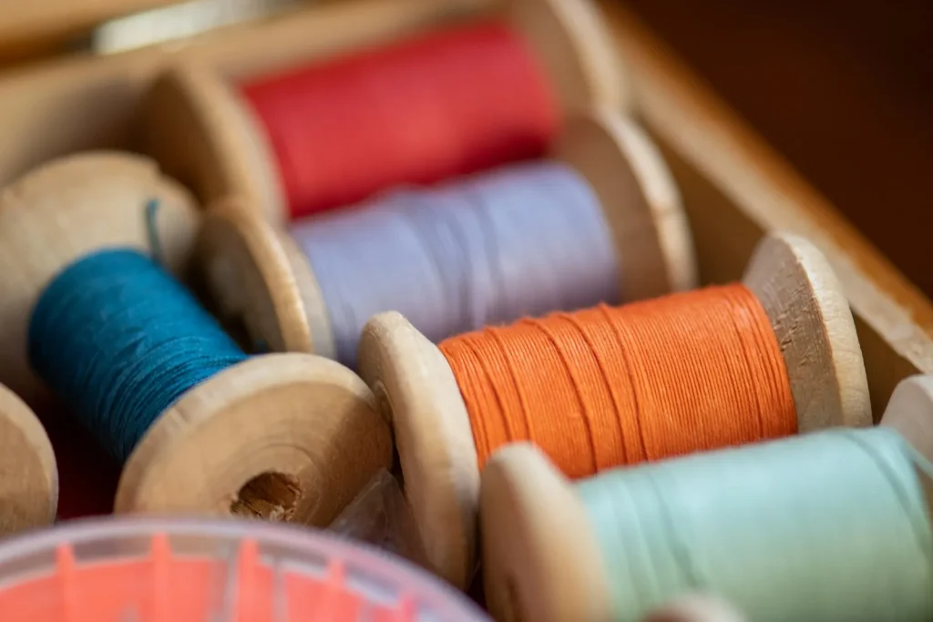 A tin of mixed vintage bobbins wound with old thread