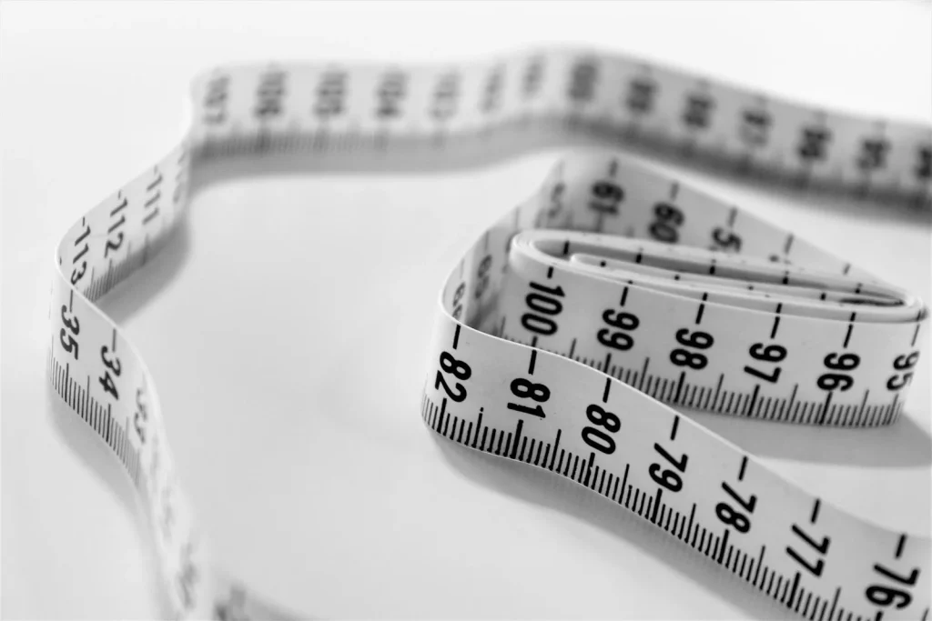 Checking the width of a sewing machine bobbin against a metal ruler